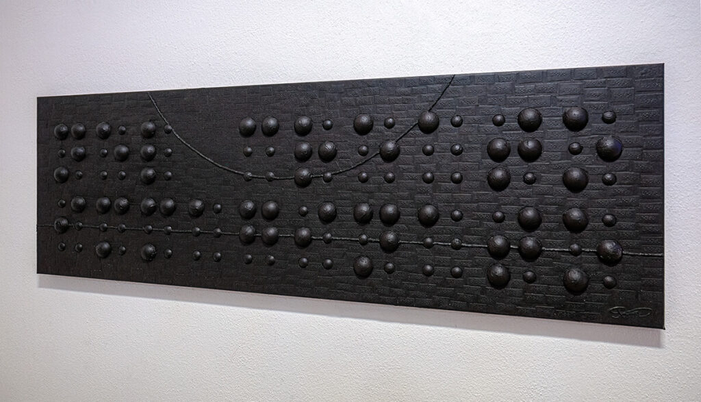 Opera d’arte Nel creato immaginato di Jona, superficie scultorea nera con rilievi sferici in Braille
