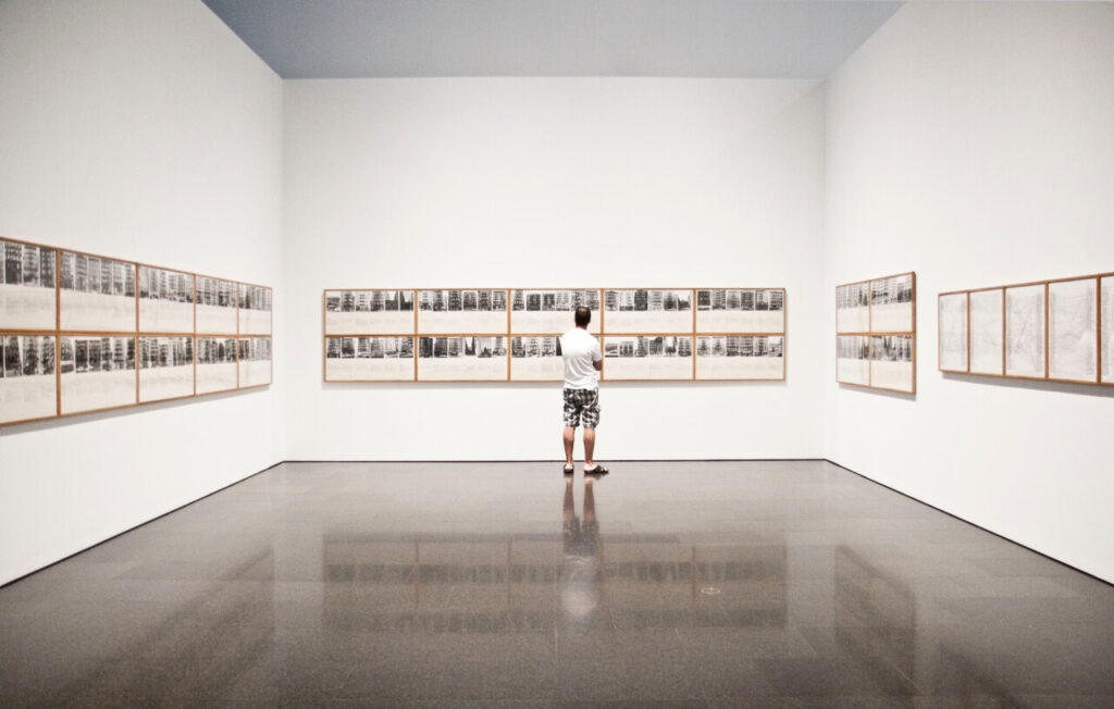 Visitatore osserva l’installazione “Shapolsky et al. Manhattan Real Estate Holdings” di Hans Haacke al MACBA di Barcellona